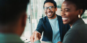Smiling man with glasses reaching to shake someone's hand