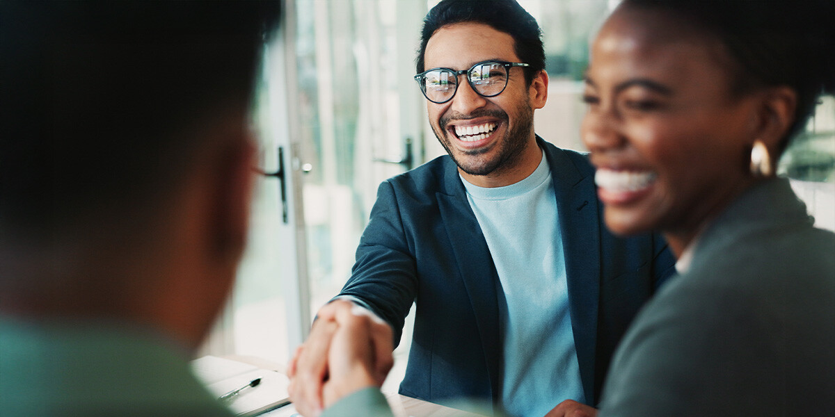 Smiling man with glasses reaching to shake someone's hand