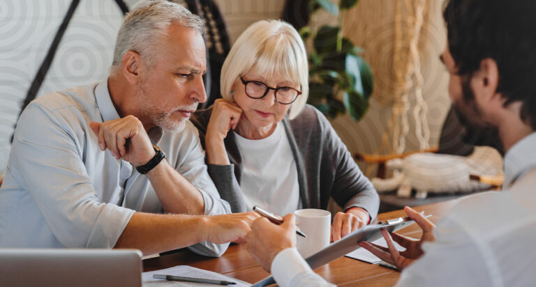 An older couple reviewing retirement planning software for advisors with a professional on a tablet.